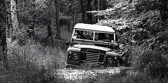Foto em preto e branco de ônibus e carro na floresta
Descrição gerada automaticamente